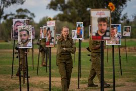 An Israeli soldier stands near photos of people killed or taken captive in an attack by Hamas
