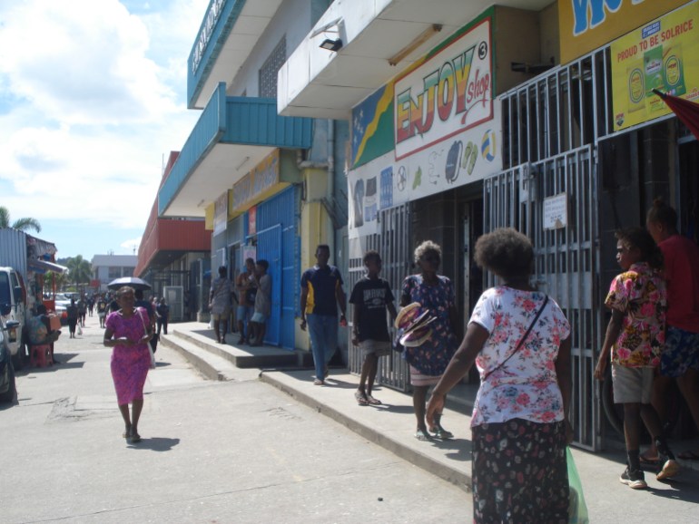 People on the streets of Honiara. There are shops along one side of the road