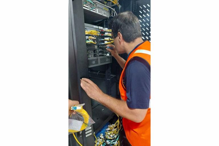 Engineer in orange vest working on a server tower
