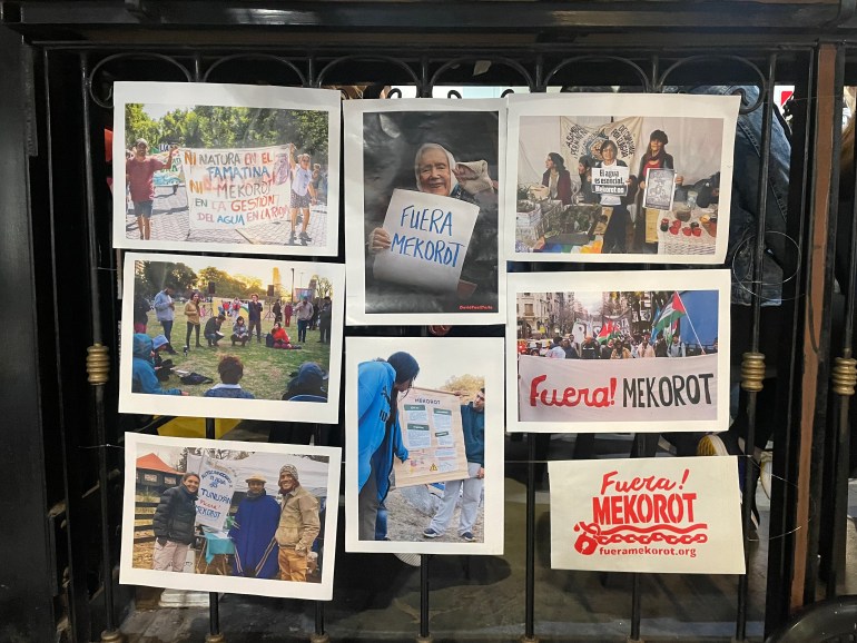 A collage of photos hang on a metal gate, showing protesters in Argentina holding up signs against the Israeli water company Mekorot