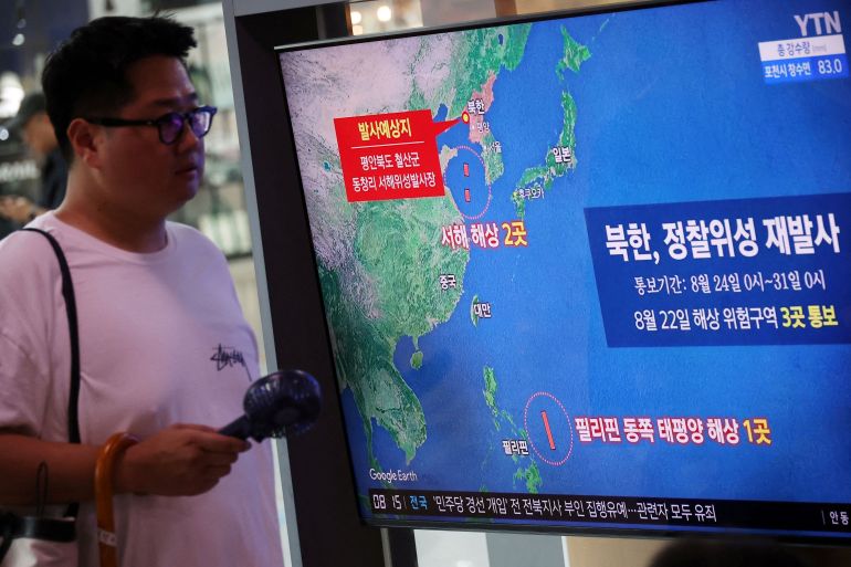 A man walks past a TV broadcasting a news report on North Korea firing a space rocket, at a railway station in Seoul, South Korea, August 24, 2023. REUTERS/Kim Hong-Ji/File Photo
