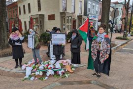 Activists stand on street corner by display depicting Palestinian children killed by Israeli attacks on Gaza