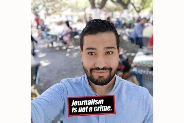 Photo of smiling Mustapha with 'Journalism is not a crime' at the bottom