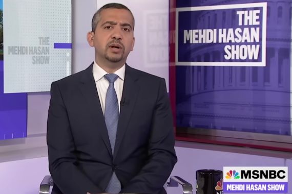Mehdi Hasan, in a suit and tie, on a TV set in front of a sign that says, "The Mehdi Hasan show."