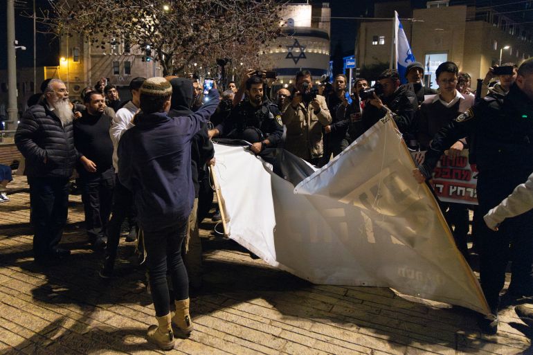 Israeli police confiscate racist banners from demonstrators in tzahal square