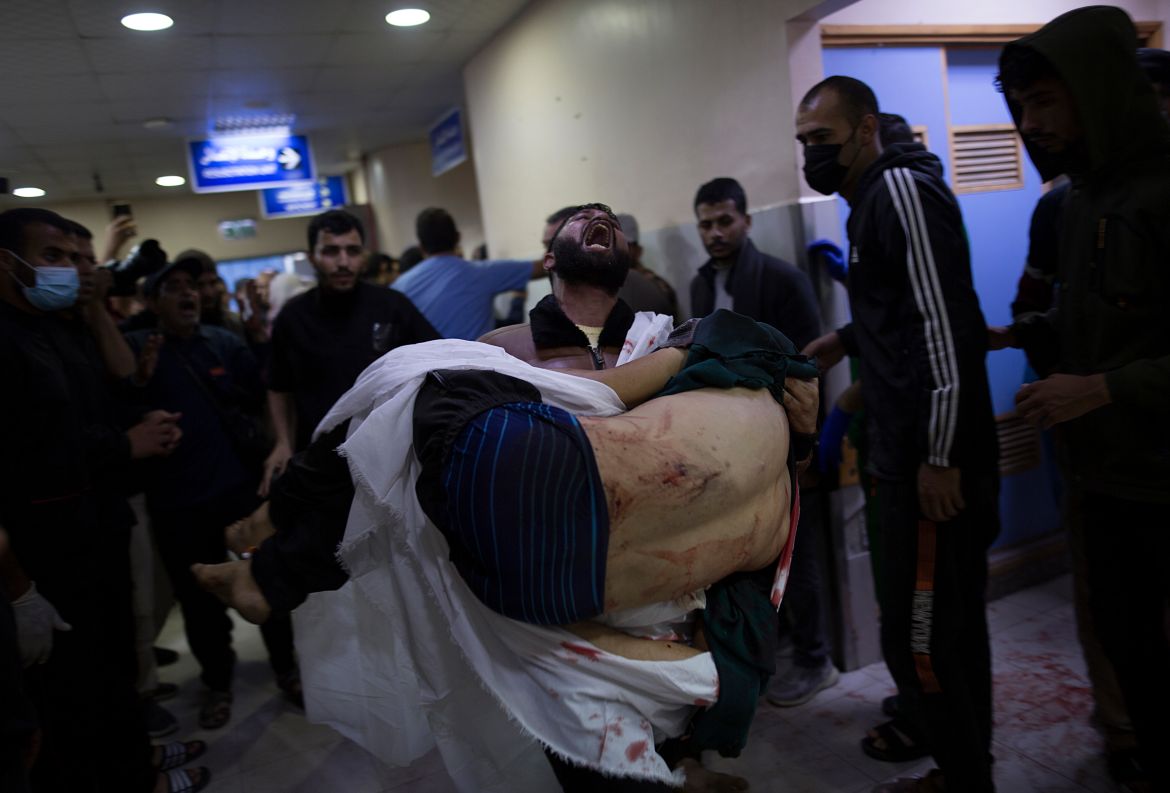 A Palestinian carries a wounded person inside Nasser Hospital in Khan Yunis, southern Gaza Strip, 03 December 2023