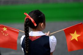 A girl holds the Chinese and Vietnamese flags