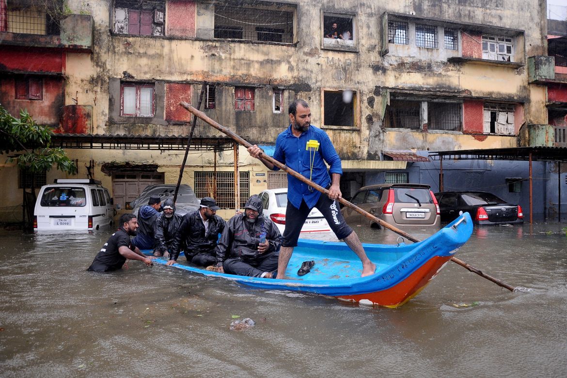 People move in a boat past partially submerged vehicles in a residential area following heavy rains ahead of Cyclone Michaung in Chennai, India, December 4