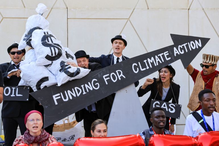 Climate activists in costumes and with props, depicting oil and gas leaders