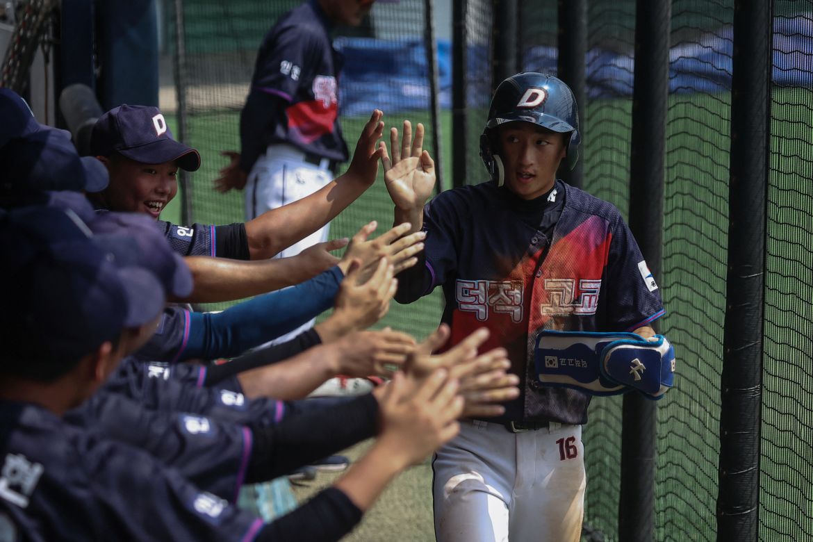 Kim Seo-jun, from the Deokjeok High School baseball team, high-fives his teammates after coming into home base, during their first game of the 51st Bonghwang High School Baseball Tournament in Seoul, South Korea.