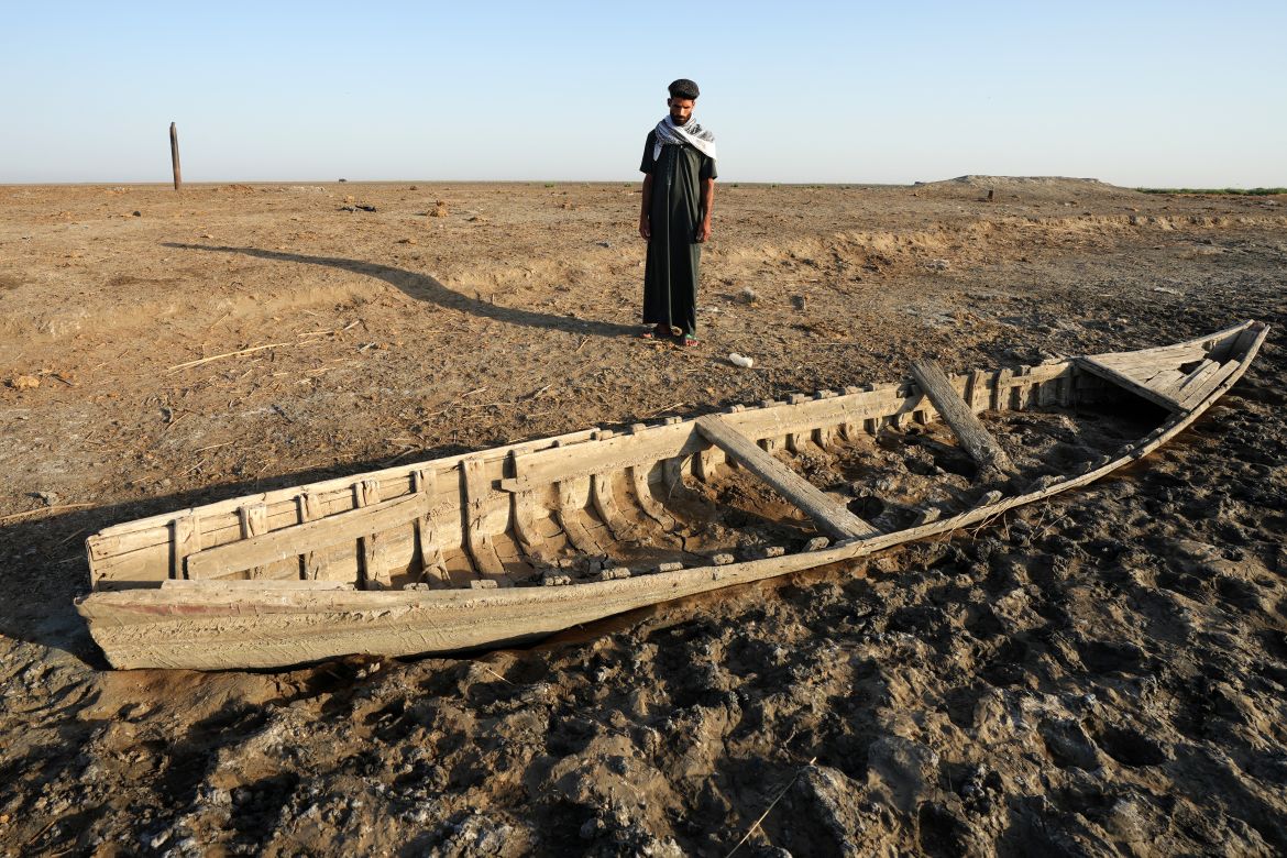 An Iraqi man looks at a grounded boat along a dried-up bank in the Chibayish marshes in Iraq's southern Dhi Qar province.