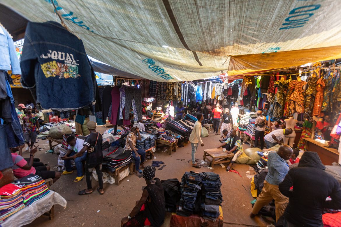 Sellers offering second-hand clothes wait for costumers at a market in Kampala.