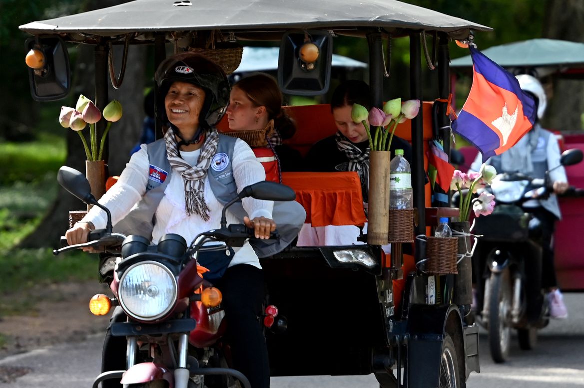 This photo taken on November 17, 2023 shows female Tuk Tuk driver Kim Sokleang transporting her passengers near the Bayon temple at the Angkor complex in Siem Reap province.