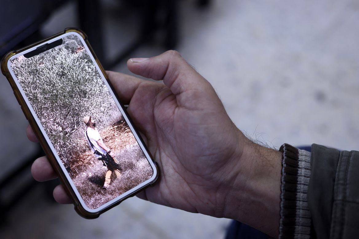 A relative of late Palestinian Bilal Saleh, shows a picture of an armed Israeli settler, at the village of As-Sawiyah, south of Nablus in the occupied West Bank.