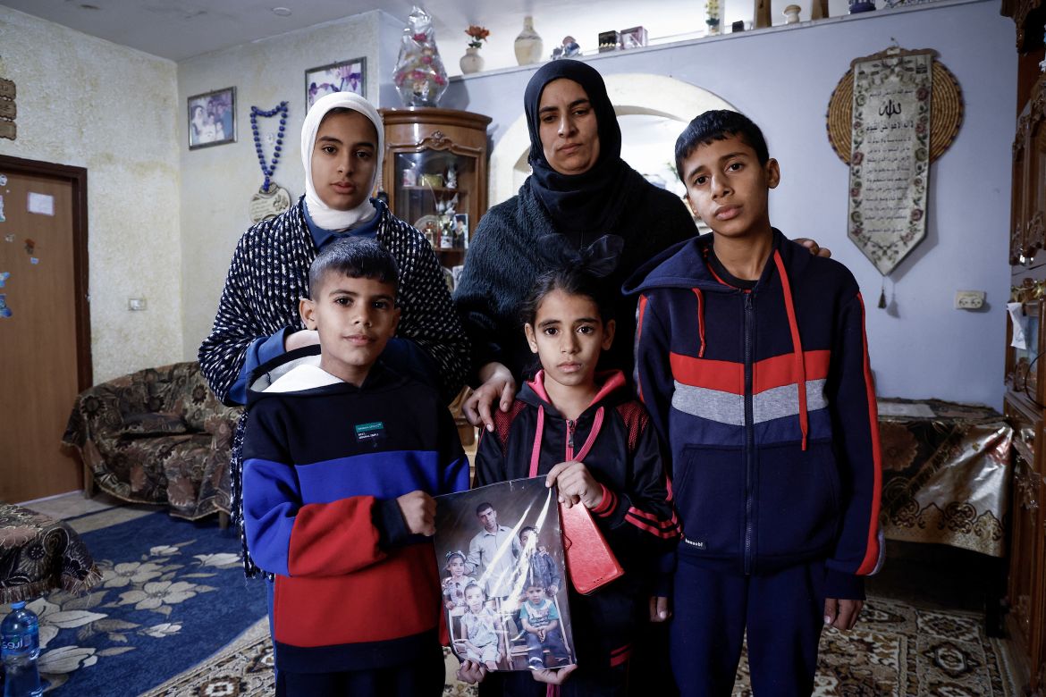 Ikhlas, the widow of Palestinian Bilal Saleh, poses with her children as they hold a picture of their late father at the village of As-Sawiyah, south of Nablus in the occupied West Bank.