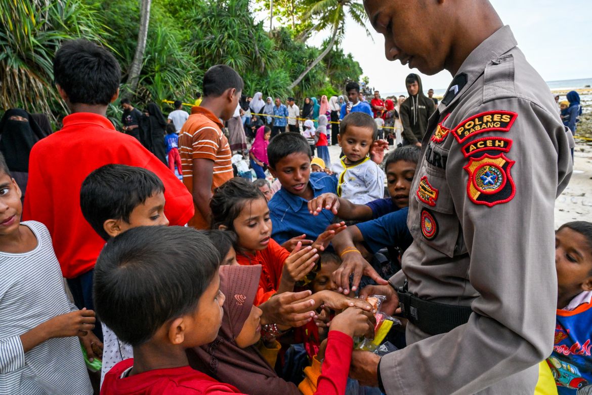 A policeman gives biscuits to Rohingya refugee children at a beach on Sabang island, Aceh province on December 2