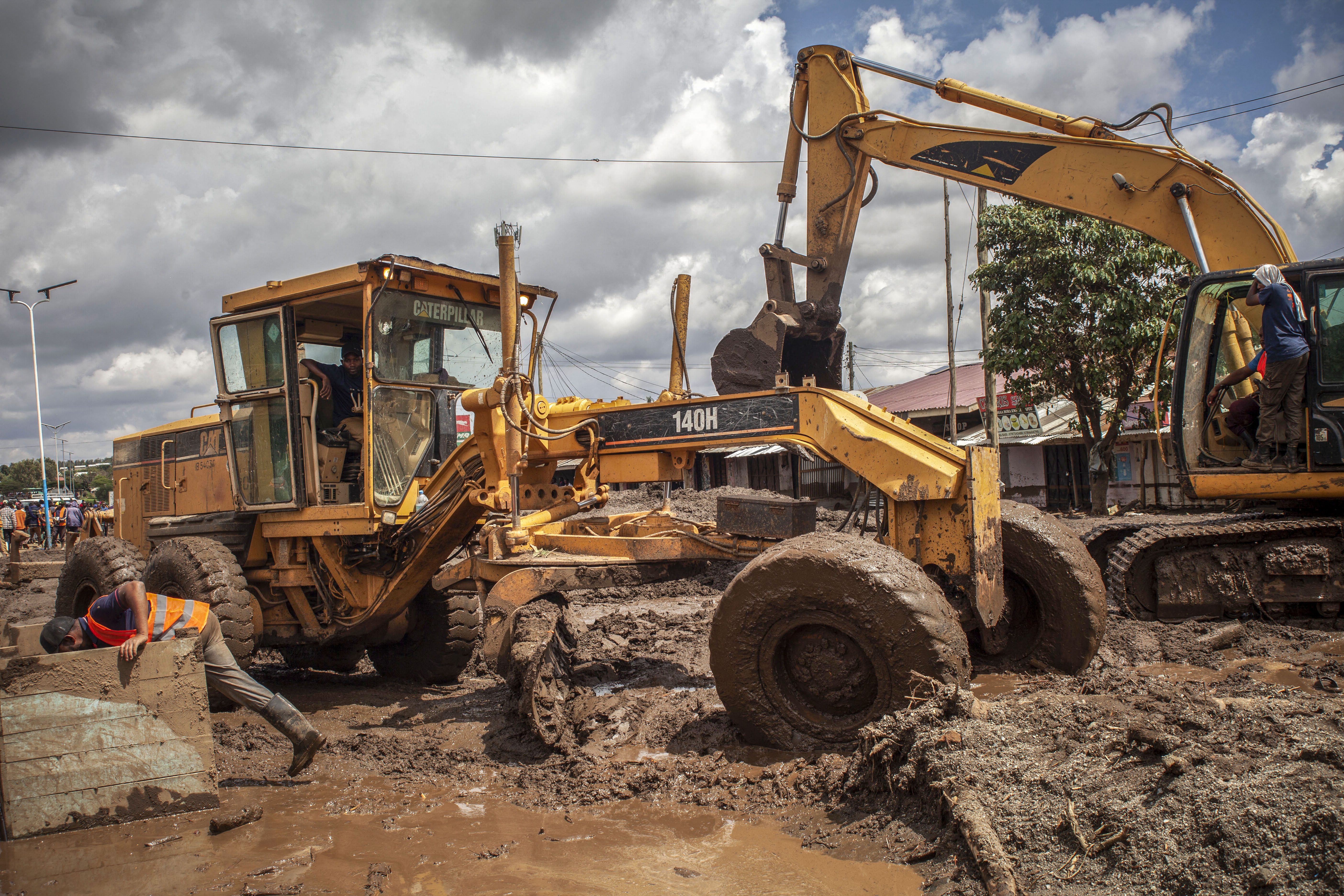 Workers remove mud from a street using excavators following landslides and flooding triggered by heavy rainfall in Katesh, Tanzania.