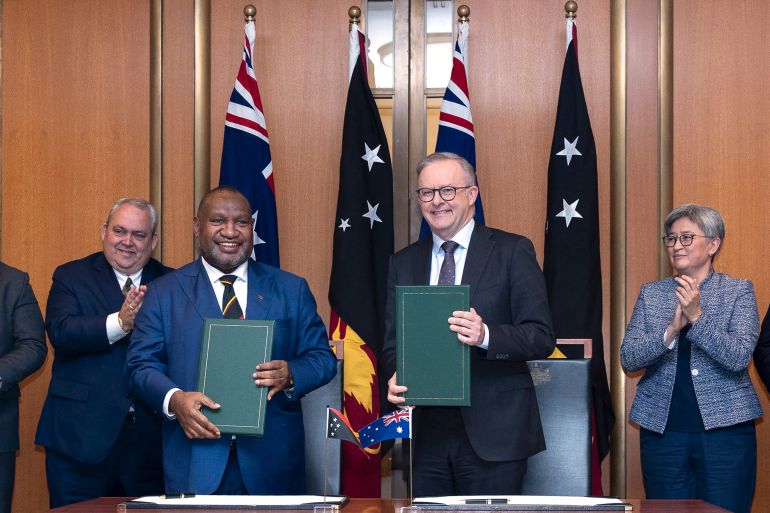 Australia's Prime Minister Anthony Albanese and PNG's Prime Minister James Marape at the official signing ceremony for the security pact. They are each holding a copy of the documents. Their countries flags are behind them.