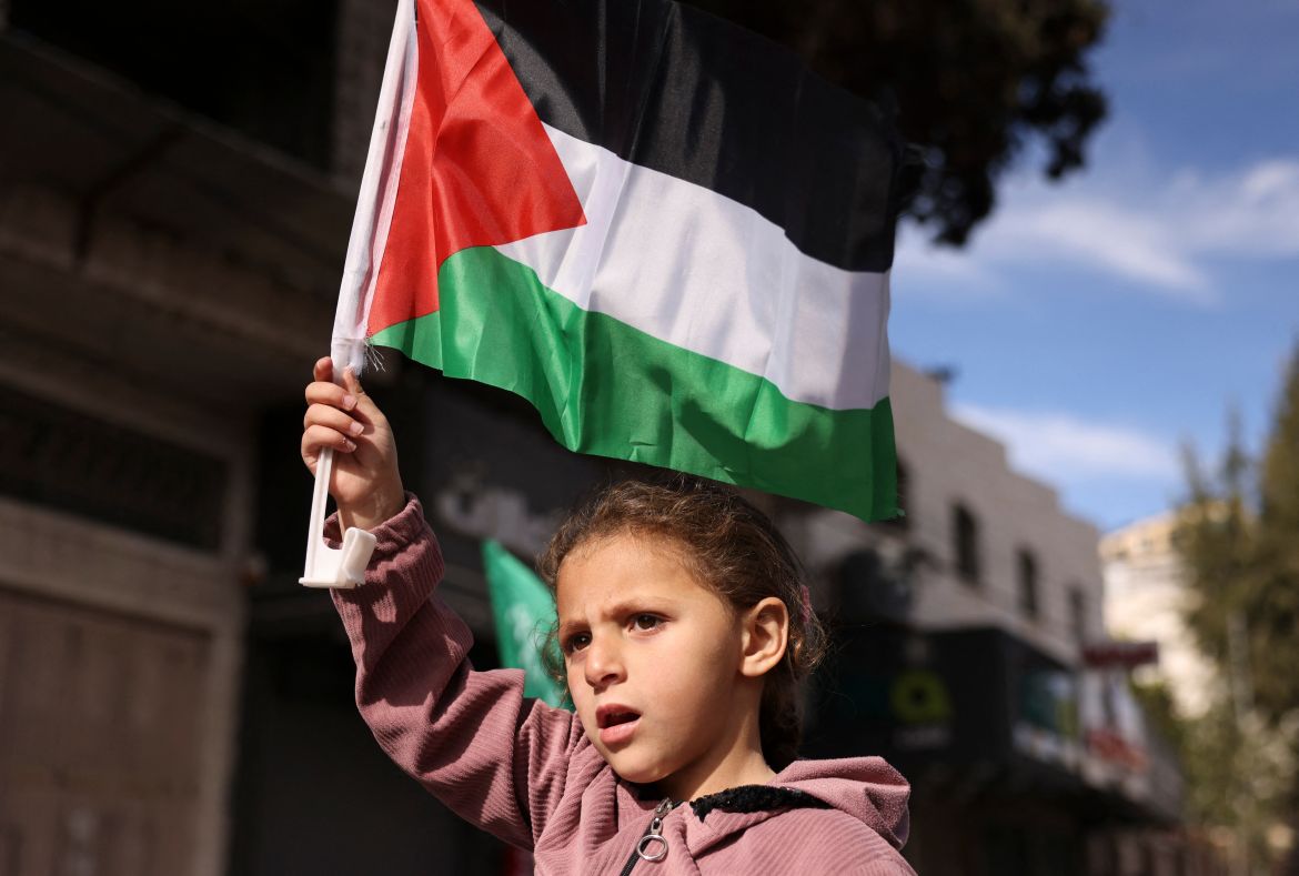 A girl lifts a national flag during a demonstration supporting the Palestinian Hamas group after the Friday prayer in Hebron city in the occupied West Bank on December 8