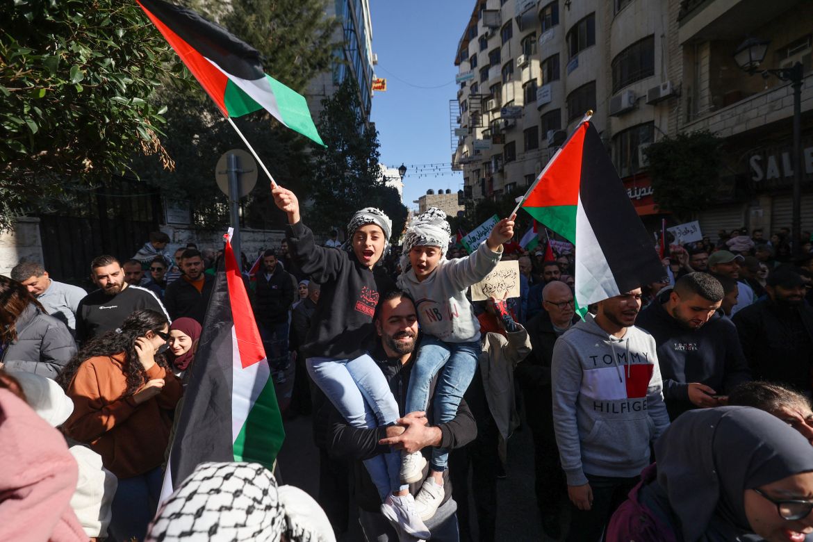 Palestinians lift national flags and chant slogans during a rally amid a general strike in Ramallah city in the occupied West Bank in solidarity with Gaza on December 11