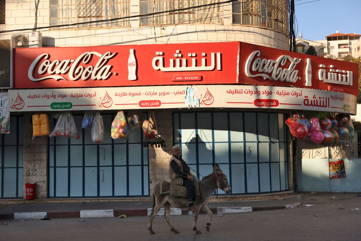 A man rides his donkey past a shuttered shop during a general strike in solidarity with Gaza, in the occupied West Bank city of Hebron, on December 11