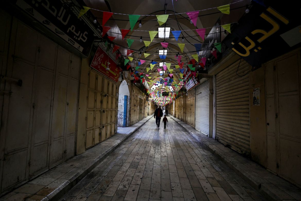 People walk past shuttered shops during a general strike in solidarity with Gaza in the occupied West Bank city of Nablus on December 11