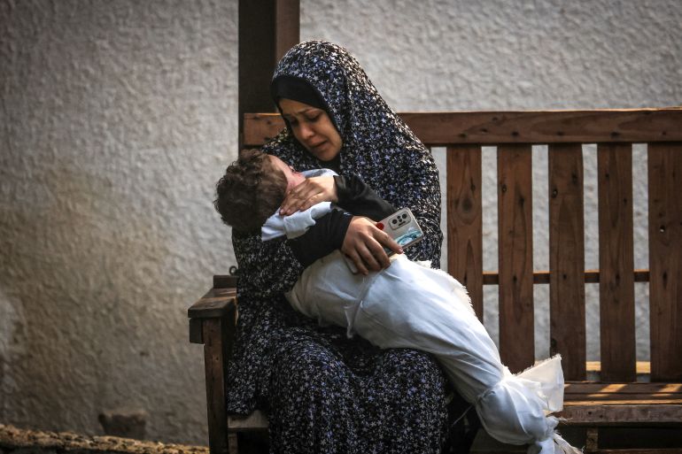 A woman from the Palestinian Ashour family holds the body of a baby who was killed in Israeli bombardment, on December 14, 2023, at Najar hospital in Rafah