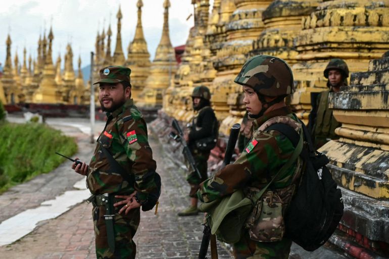 Ta'ang National Liberation Army (TNLA) standing guard in a temple area of a hill camp seized from Myanmar's military in Namhsan Township. The temple has golden stupas.