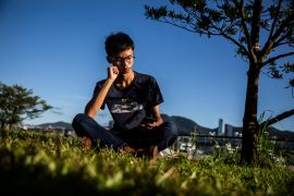 Tony Chung pictured in Hong Kong in 2020. His sitting in the grass looking at his phone.