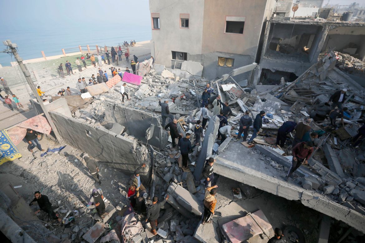An aerial view of Palestinian search and rescue team and civilians gathering to conduct search and rescue operation among rubble of buildings in Deir Al Balah