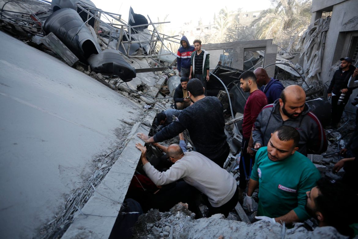 Residents and civil defense teams conduct a search and rescue operation among demolished buildings after Israeli attacks in Deir Al-Balah, Gaza.