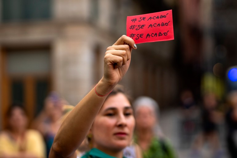 A demonstrator holds a red card reading in Spanish "it is over" during a protest against the President of Spain's soccer federation Luis Rubiales and to support Spain's national women's soccer player Jenni Hermoso in Barcelona, Spain, Monday, Sept. 4, 2023. Spain faces reckoning over sexism in soccer after federation head kisses player at Women's World Cup. (AP Photo/Emilio Morenatti)