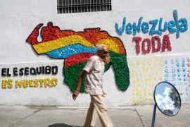 A man walks in front of a mural of the Venezuelan map with the Essequibo territory included, in Caracas, Venezuela [File: Matias Delacroix/AP Photo]