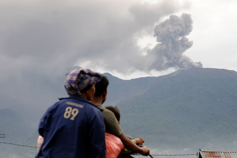 Motorists ride past as Mount Marapi spews volcanic materials during its eruption in Agam, West Sumatra, Indonesia