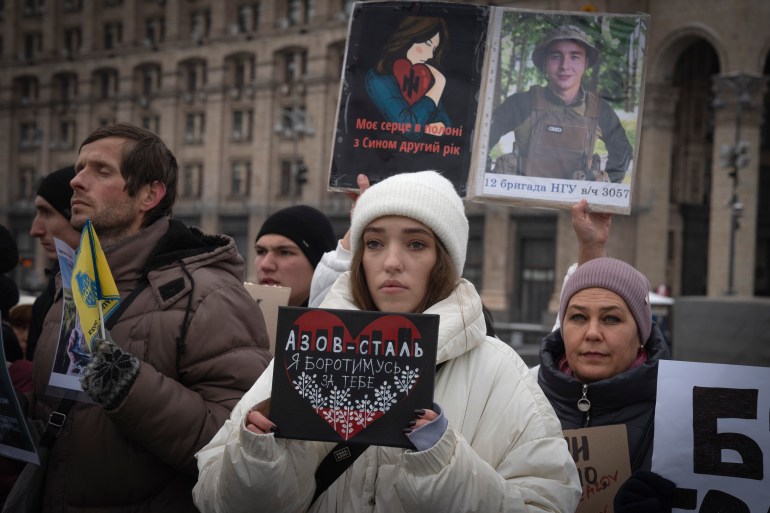 A Ukrainian woman taking part in a protest demanding soldiers taken captive by Russia be freed. She is holding a placard.
