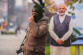 An Indian policeman stands guard near a cutout portrait of Indian Prime Minister Narendra Modi displayed at the main market in Srinagar, Indian controlled Kashmir.