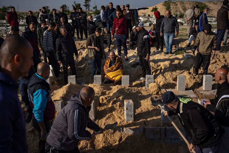 Palestinians bury their relatives killed in the Israeli bombardment of the Gaza Strip, at a cemetery in Rafah, southern Gaza, Tuesday, Dec. 19