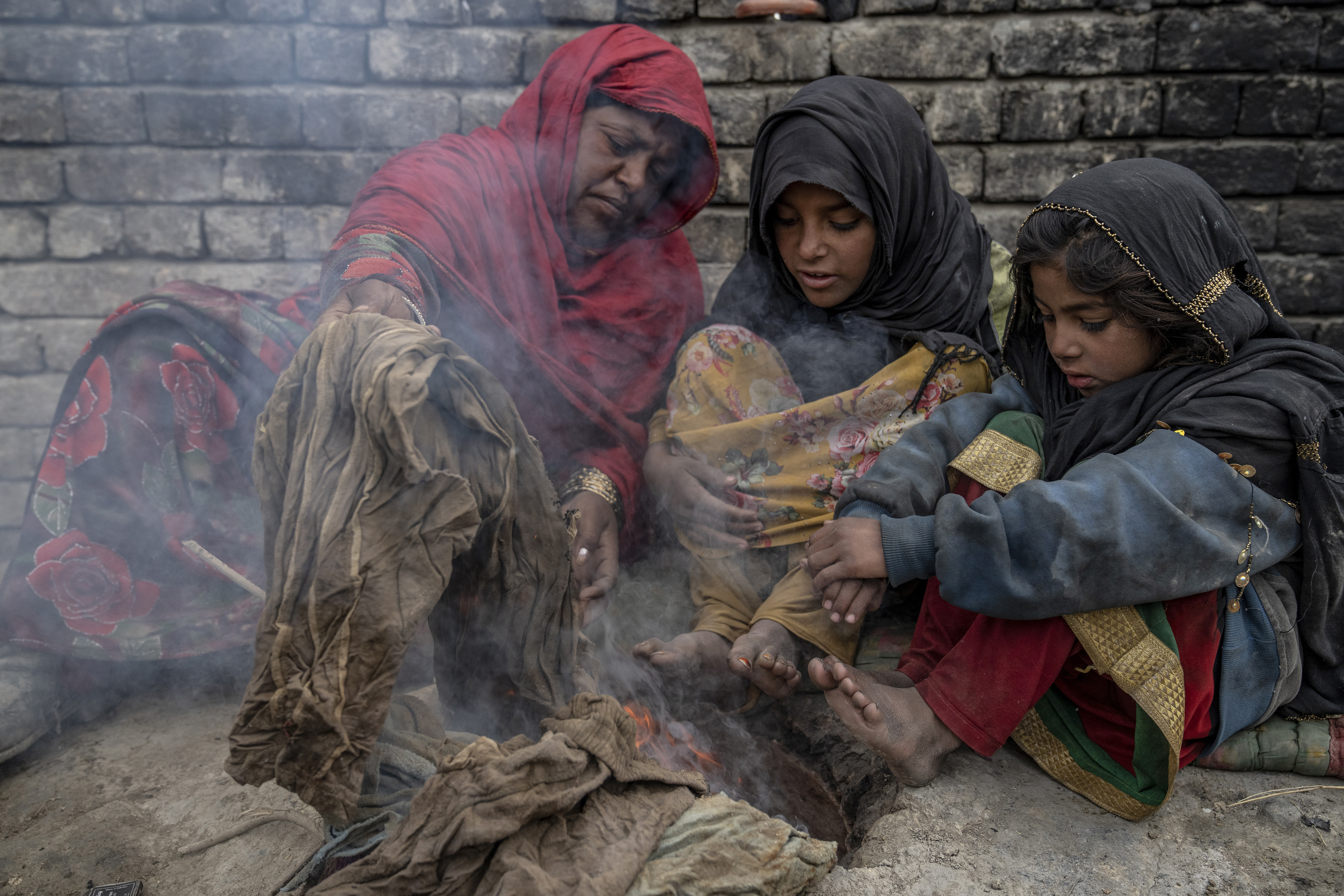 A family who were forced to leave their home, warms up by burning garbage in a camp on the outskirts of Kabul, Afghanistan, Sunday, Jan 22