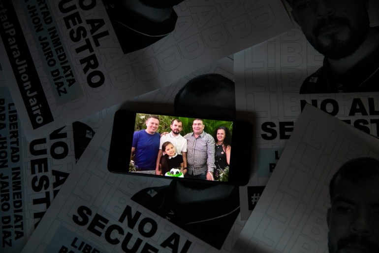 A cellphone shows a photo of Jhon Jairo Diaz among family members.