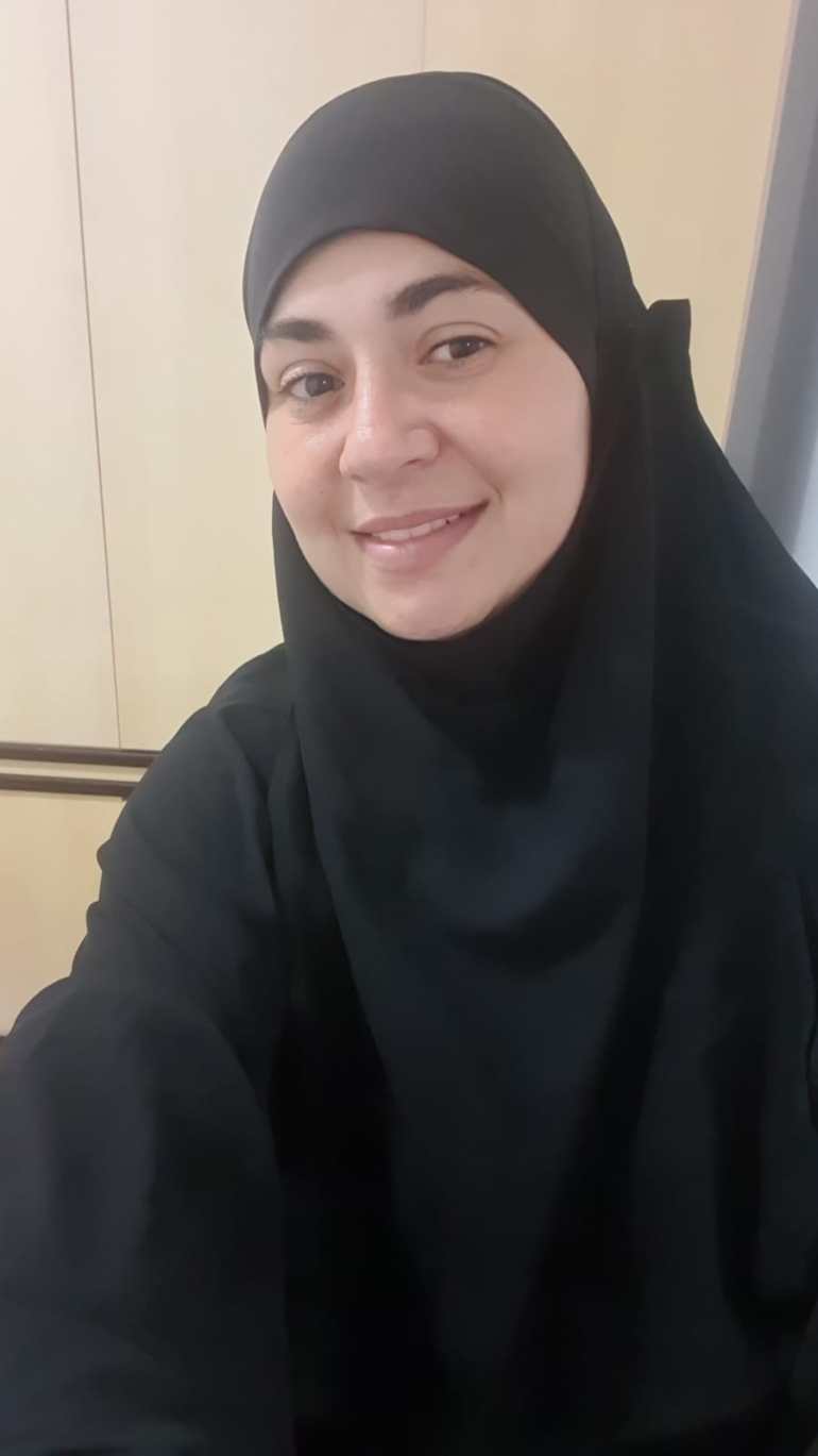 A woman wearing a black head scarf takes a selfie