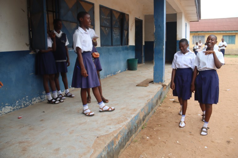 A photo of Blessing (right) and Rebecca walking outdoors in their school to get to a classroom.