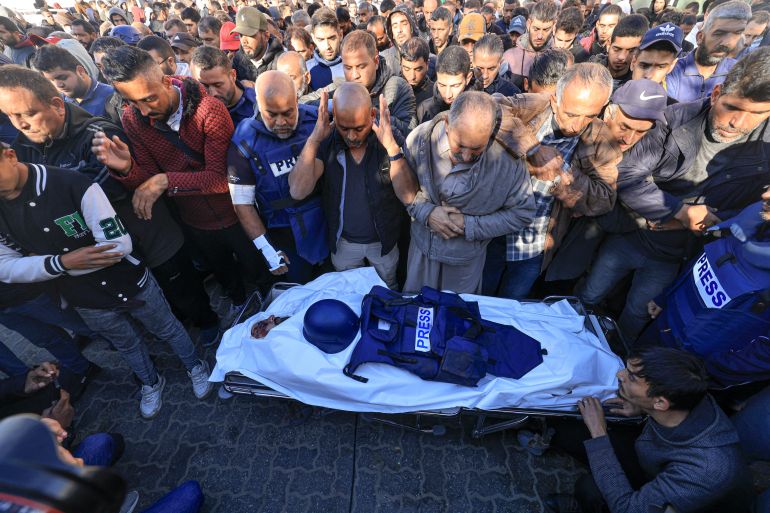 Colleagues and family members pray over the body of Al Jazeera cameraman Samer Abudaqa