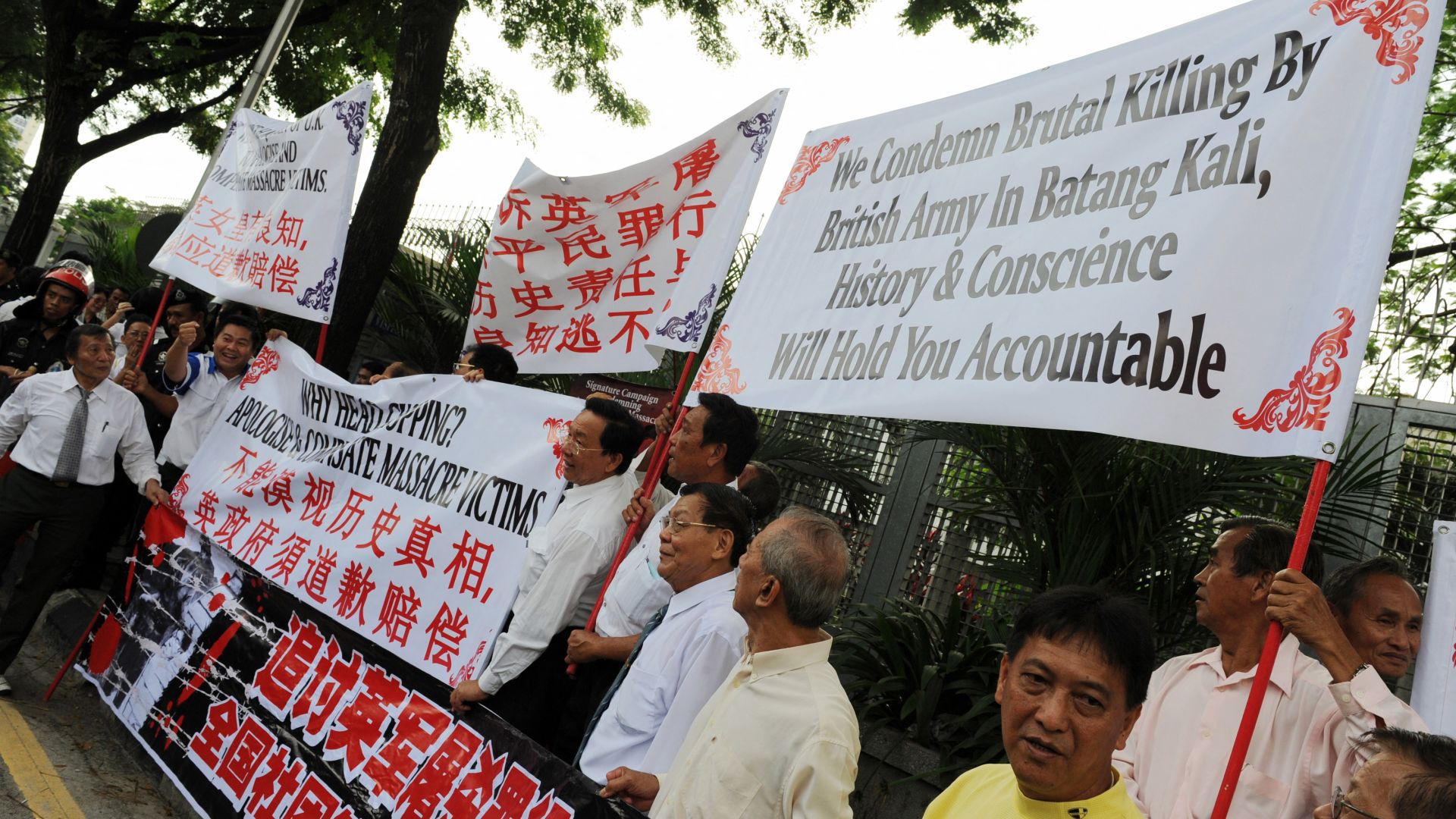 Ethnic Chinese hold banners in front of the British High Commission building in Kuala Lumpur on December 12, 2008 during a demonstration to condemn an historic Batang Kali massacre. Scores of protestors who gathered at the British High Commission building in Kuala Lumpur condemned the killing of 24 unarmed villagers by the British Army in 1948 in Batang Kali and demanded an apology from Britain and compensation to the victim's families. AFP PHOTO / Saeed KHAN (Photo by SAEED KHAN / AFP)
