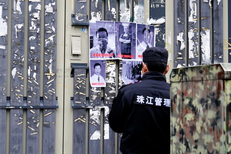 A security guard tries to take off posters in memory of late doctor Li Wenliang with other doctors at the Central Hospital of Wuhan on the anniversary of his death, in Wuhan, Hubei province, China February 7, 2021. REUTERS/Aly Song