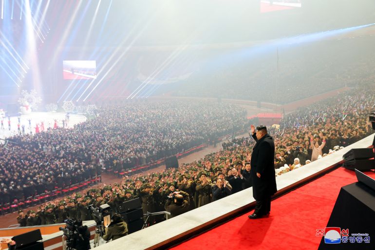 North Korean leader Kim Jong Un in a stage in front of a sea of people at a New Year celebration