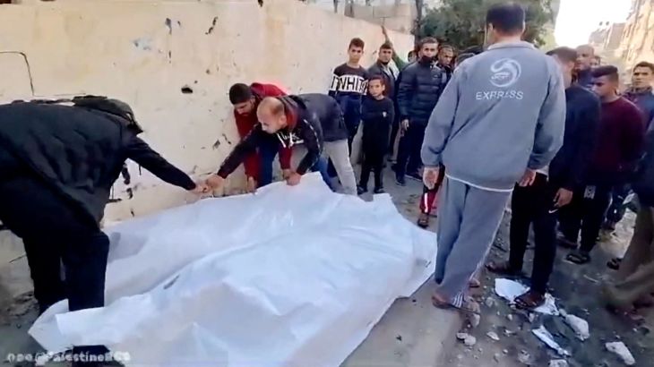 People cover bodies with a white sheet on a street following an airstrike on a house in Maghazi camp, Deir al-Balah, central Gaza,