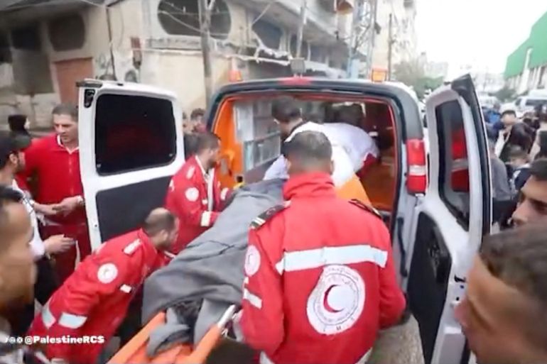 Palestine Red Crescent Society (PCRS) rescuers move a casualty into an ambulance following an attack on a PCRS building,