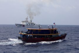 A Philippine supply boat sails near a Chinese Coast Guard ship during a resupply mission for Filipino troops stationed at a grounded warship in the South China Sea