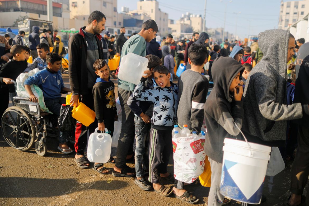 Palestinians queue as they wait to collect drinking in Rafah