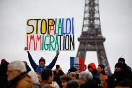 A man holds a placard as people gather in front of the Eiffel Tower to attend aa citizen march against the immigration law, surnamed "Darmanin law", in Paris, France, January 21, 2024. REUTERS/Sarah Meyssonnier TPX IMAGES OF THE DAY